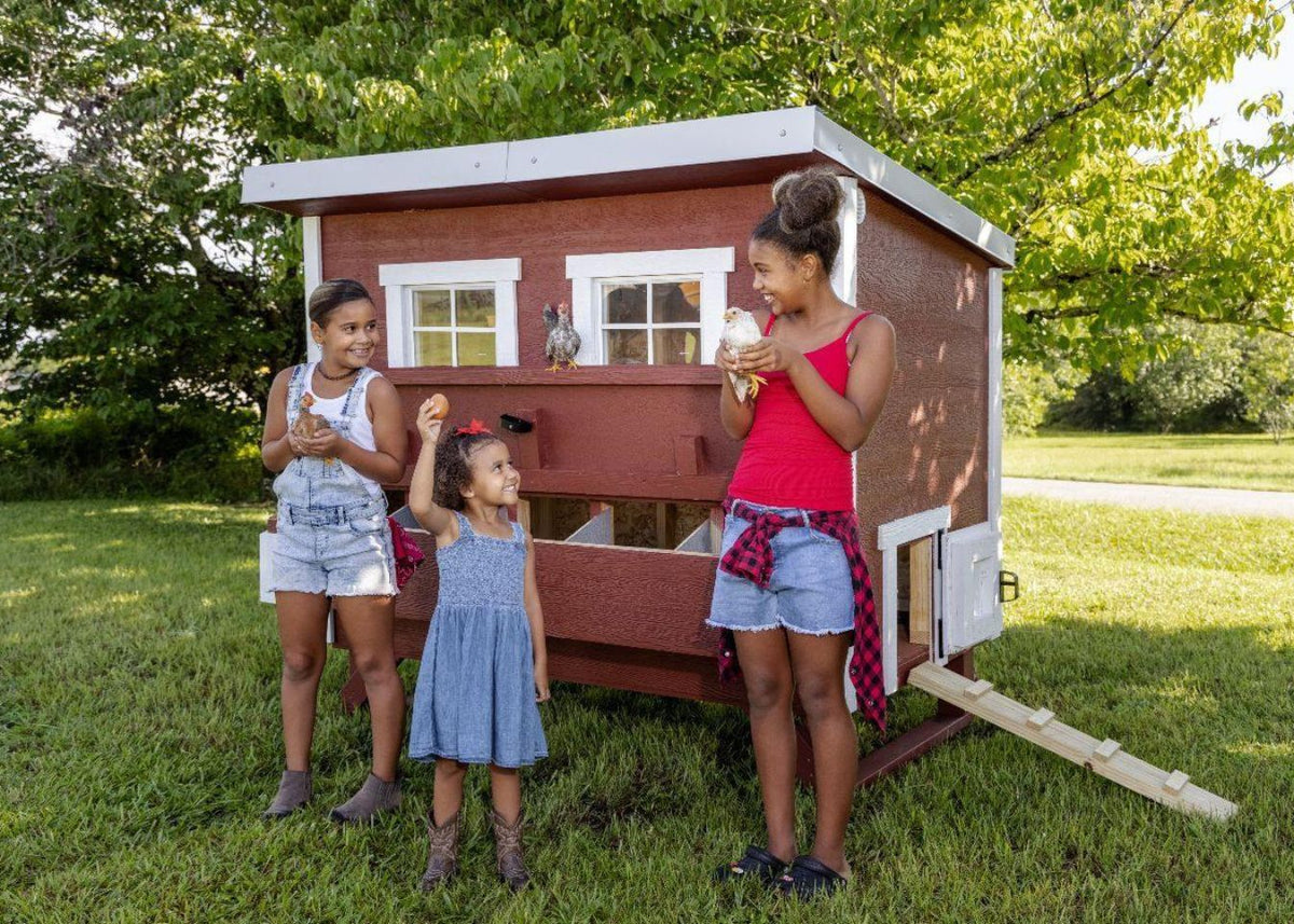 Red large chicken coop with white trim, with children in the backyard