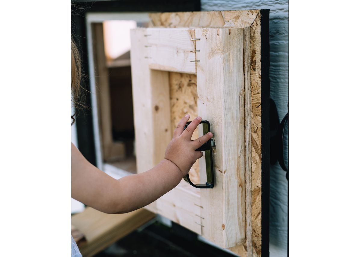Child opening the predator-proof latch on the large chicken coop
