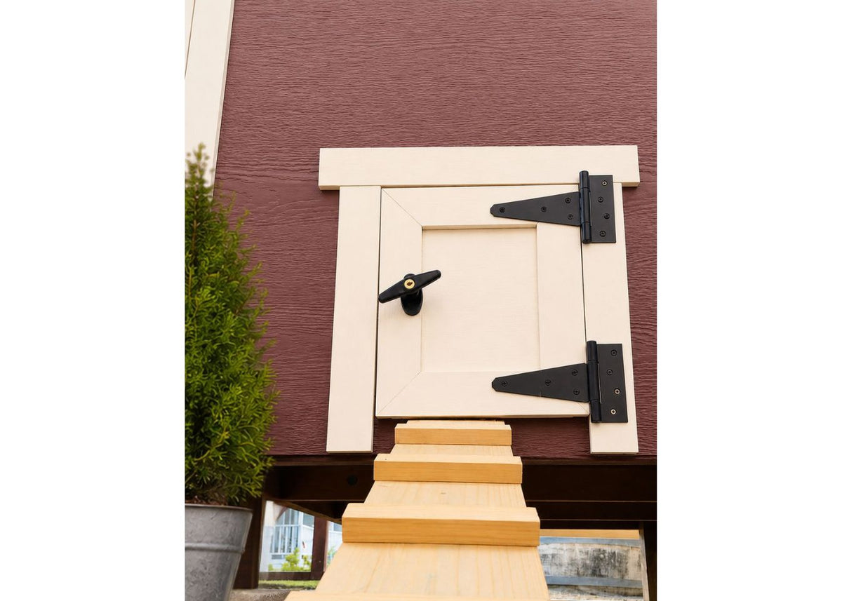 Red large chicken coop with white trim, close-up of the chicken pop door