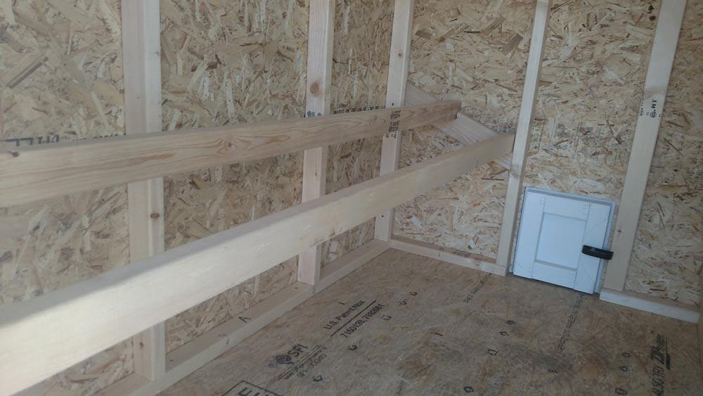 Inside the large chicken coop with roost bars and windows