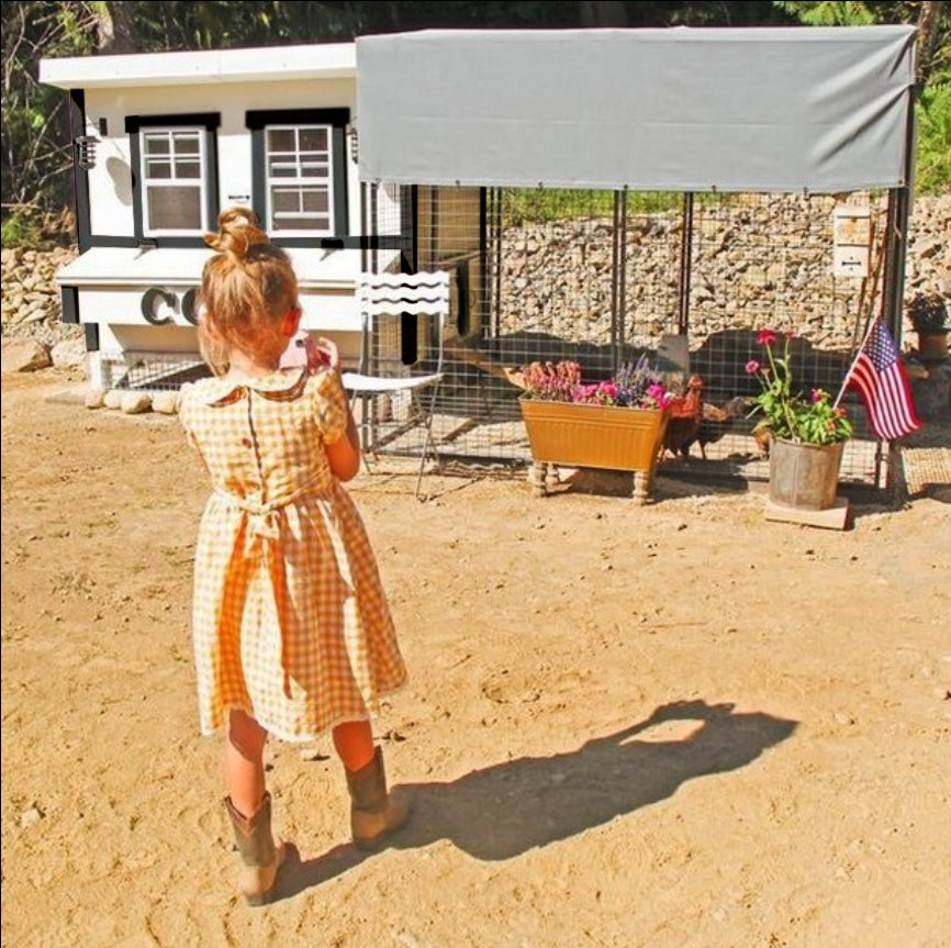 Girl standing by a white farmhouse-style large chicken coop and run