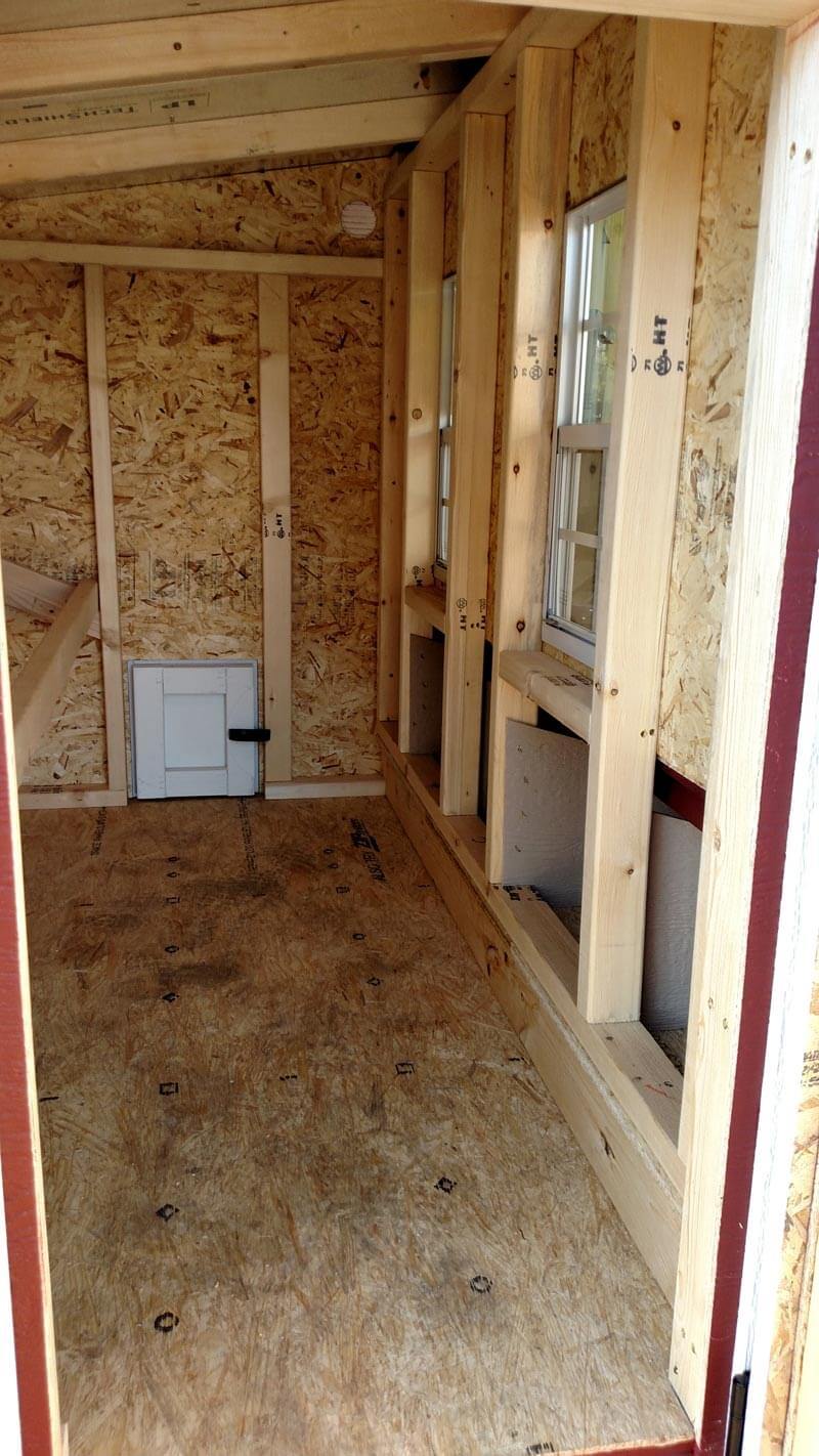 Inside the large chicken coop with roost bars and windows