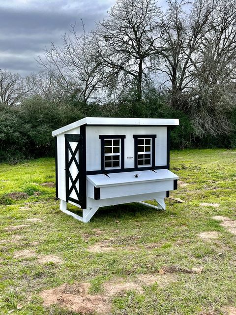 White farmhouse-style large chicken coop, set up in a backyard