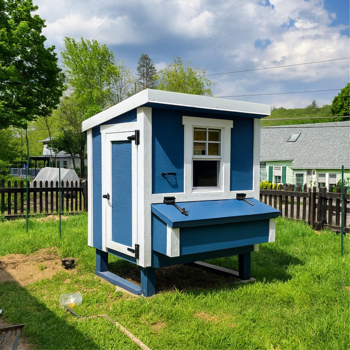 Blue medium chicken coop with white trim, set up in a backyard