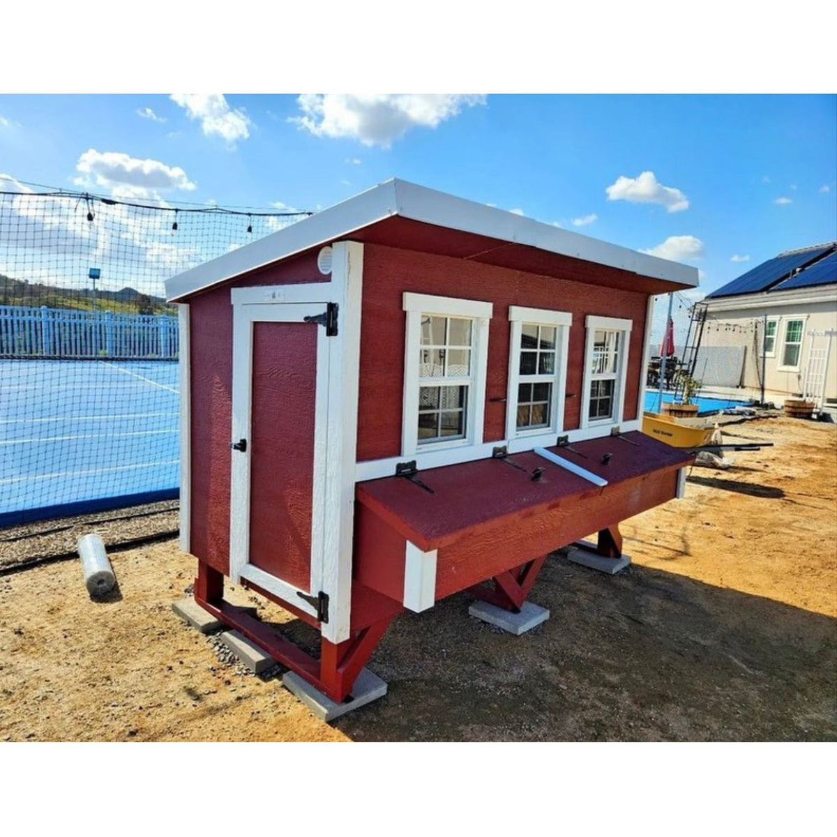 Red XL chicken coop with white trim, set up in a backyard